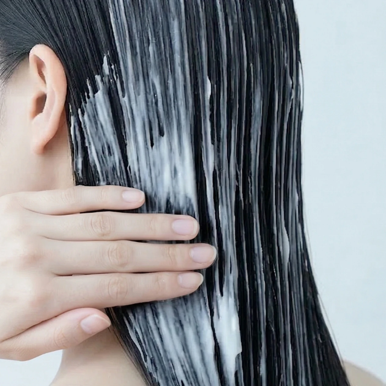 髪にヘアトリートメントをなじませる女性の後ろ姿